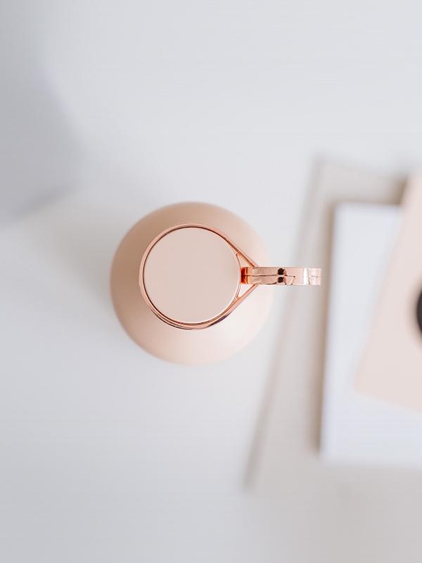 EQUA Smart Water bottle in Pink Blush Colour in the center of the image. The photo is taken from the top to bottom showing the details of the lid and rose gold details and holder ring.