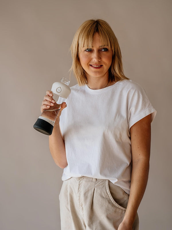 Girl smiling and holding Active White glass water bottle