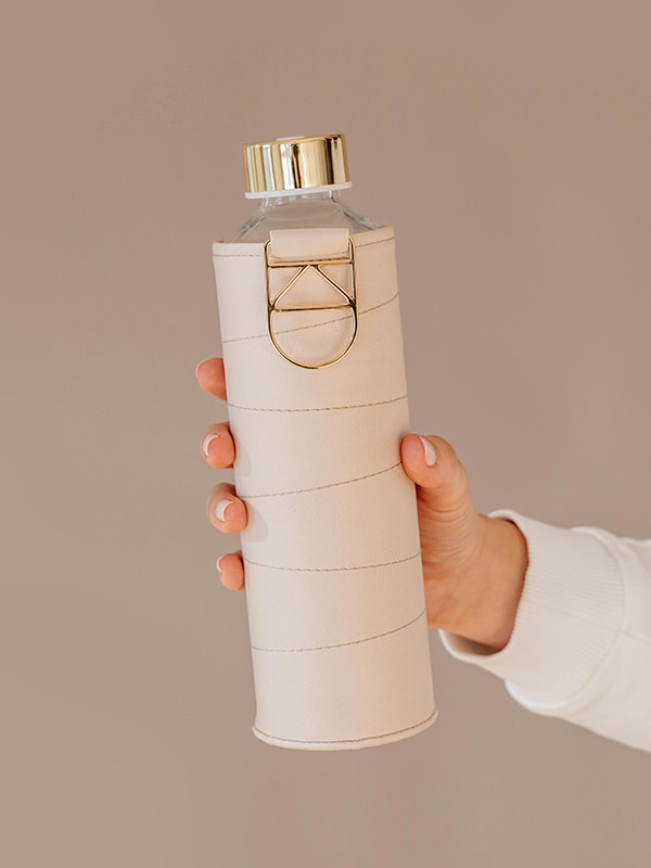 EQUA glass water bottle Beige. The bottle is being hold with hands.