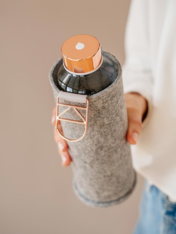 Holding in hand EQUA glass water bottle Rose Gold with rose gold lid.