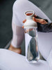 EQUA Bouteille d'eau FLOW SANS BPA, Freeze, gros plan de la bouteille tenue dans les mains par une yoga girl, design minimal, sans motif, couleur grise.