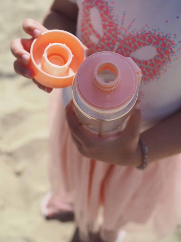 EQUA Botella de agua SIN BPA, Playground, la botella abierta sostenida por una niña muestra la tapa y la boquilla, color rosa