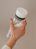 EQUA Bouteille d'eau SANS BPA, Plain White, gros plan de la bouteille tenue à la main, design minimaliste, sans motif, couleur blanche