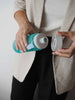 EQUA Bouteille d'eau SANS BPA, Océan, femme d'affaires tenant une bouteille d'eau dans ses mains, design minimaliste, sans motif, couleur bleue