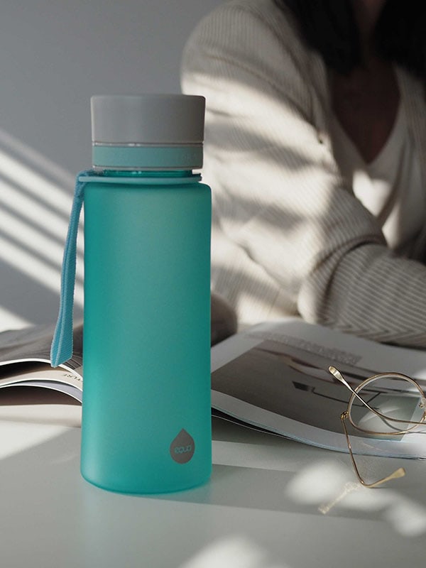 EQUA BPA FREE steklenica vode, Ocean, steklenica vode stoji na pisarniški mizi, ženska dela v ozadju, minimalistično oblikovanje, brez motiva, modra barva