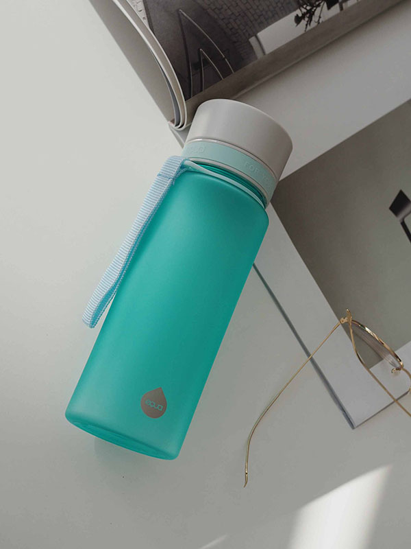 EQUA BPA BREZPLAČNA steklenica vode, Ocean, steklenica vode na pisarniški mizi, skupaj z bralnimi očali in revijo, minimalistično oblikovanje, brez motiva, modra barva