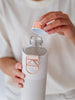 EQUA Botella de agua de cristal reutilizable Sage con tapa de piel sintética blanca y gris y asa metálica y tapa dorada