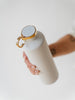 EQUA Pokrov pametne vodne steklenice z zlatimi detajli in držalom za prstan. Steklenica pametne vode iz nerjavečega jekla se poveže s telefonom in meri vnos vode in pošilja sijoče opomnike, da vzamejo požir vode.